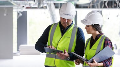 Woman in construction attire with male colleague. 
